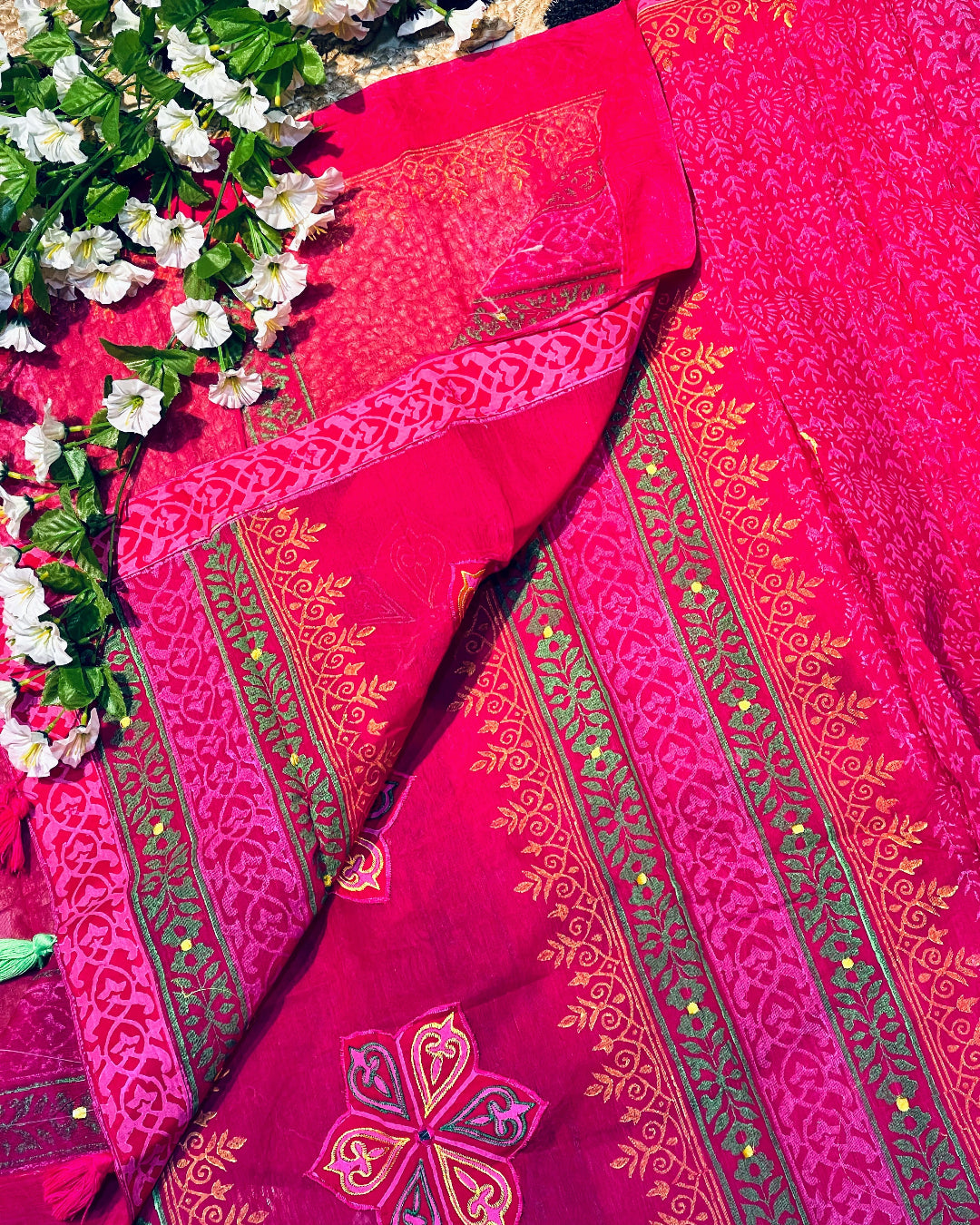 Red saree with intricate gold patterns on a floral background