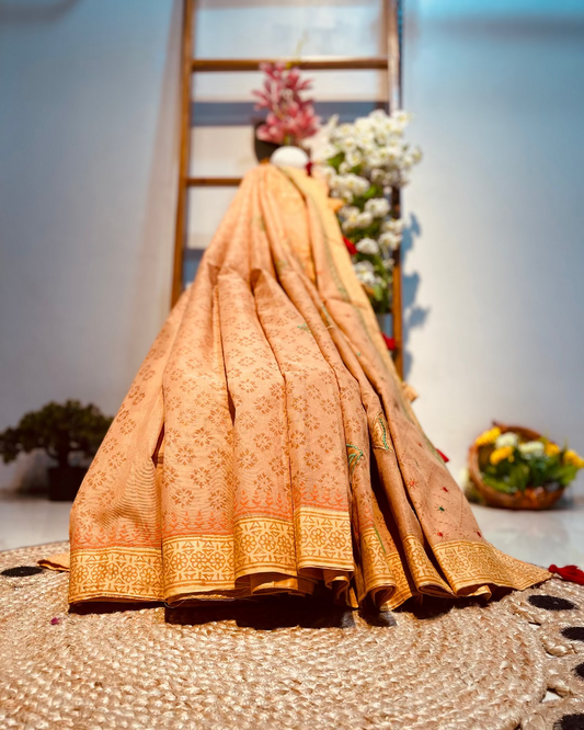 Traditional embroidered saree on a textured surface with decorative elements in the background