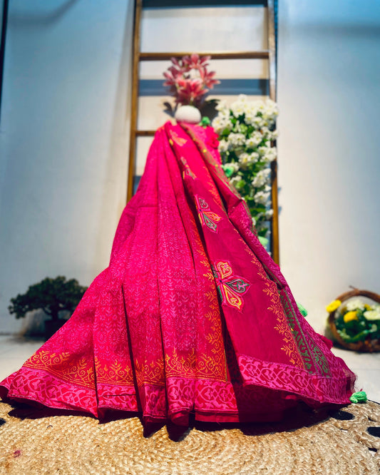 Pink embroidered saree on a mannequin against a floral backdrop