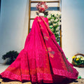 Pink embroidered saree on a mannequin against a floral backdrop