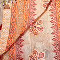 Close-up of a fabric with intricate red patterns on a beige background