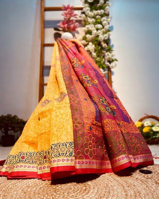 Two colorful sarees draped over a woven surface with flowers in the background