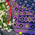 Colorful embroidered fabric with geometric patterns on a floral background