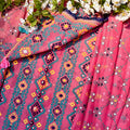 Pink fabric with colorful patterns and white flowers on a pink background