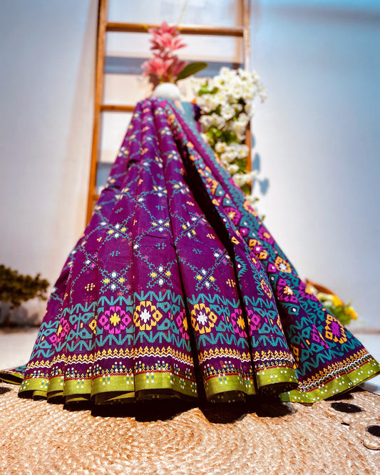 Colorful embroidered fabric draped over a wooden ladder with flowers in the background