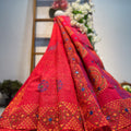 Red embroidered fabric with intricate patterns draped over a wooden ladder.