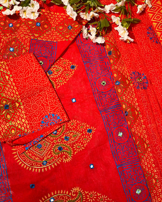 Red fabric with blue and gold patterns and white flowers on a red background