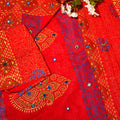 Red fabric with blue and gold patterns and white flowers on a red background