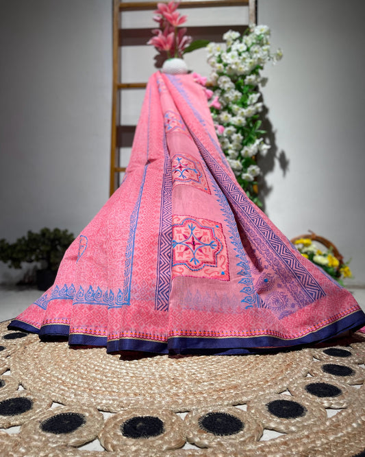 Pink embroidered fabric draped over a chair with flowers in the background
