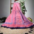 Pink embroidered fabric draped over a chair with flowers in the background