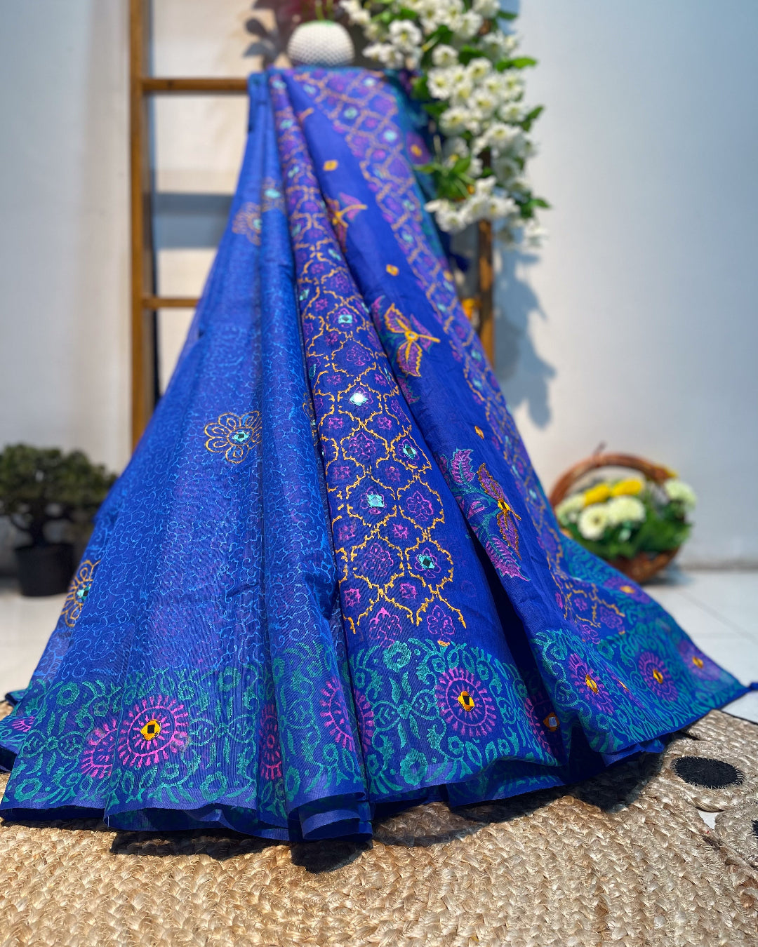 Blue embroidered saree with intricate patterns on a textured surface.