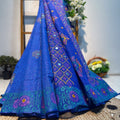 Blue embroidered saree with intricate patterns on a textured surface.