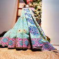 Colorful patterned fabric draped over a surface with flowers in the background